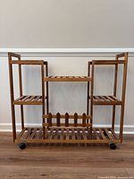 Front view of wooden plant stand showing six shelves and casters