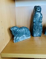 Walrus/seal sculpture beside standing human figure on shelf