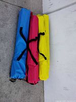 Three stacked carry bags in blue, red and yellow corresponding to folding camping chairs