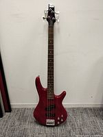 Full view of red Ibanez 4-string electric bass guitar standing upright