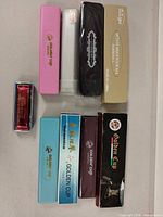 All nine boxed harmonicas laid out, showing brand names and cases