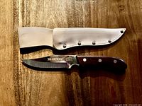 Knife and sheath laid flat on wood surface