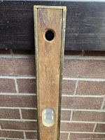 End section of wooden level showing brass edge and circular plumb opening