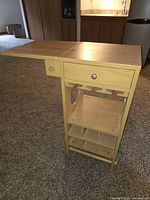 Front angle showing drop leaf extended, drawer, utensil pegs, towel rack, lower bottle rack