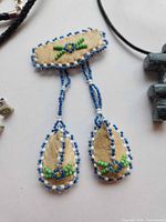 Front view of beaded brooch with partial necklaces