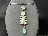 Front view of pendant showing abstract spine and turquoise drop