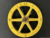 Front view of yellow cast iron wheel wall clock