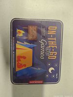 Front of sealed Kikkerland On-The-Go Games tin