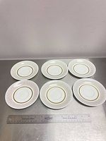 Six Royal Albert Capri saucers arranged front view with ruler for scale