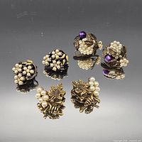 All three pairs of clip-on earrings displayed on reflective surface