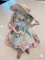 Front view of ceramic girl figurine showing dress, hat, hair, boots, animal detail