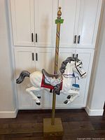 Full view of carousel horse on pole and base