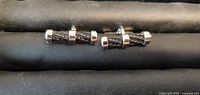 Front view of both cufflinks showing chrome ends and black twisted cable center
