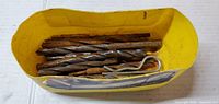 top view of yellow container holding assorted drill bits and metal pieces