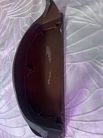 Underside of black plastic shelf showing curved shape, mounting holes, surface wear