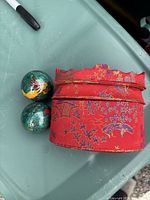 Two Baoding balls beside red brocade storage box
