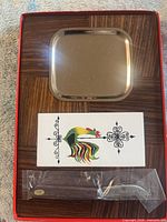 Box interior showing metal tray, rooster tile, spreader in sleeve, woodgrain base