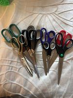 All nine scissors spread out showing colors, sizes and handles