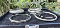 All six bangles displayed on black case showing variety of widths and textures