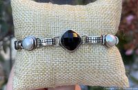 Front view showing central faceted black stone and pearl cabochons