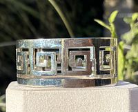 Front view showing openwork Greek key design and silver-tone finish