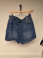 Front view of blue denim shorts hanging on hanger