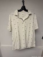 Front view of white patterned polo shirt on hanger