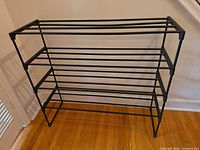 front view of black plastic four-tier shoe rack