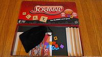 Open box showing board, pouch, letter tiles, racks, rule booklet