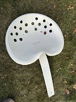 Top view of white cast iron tractor seat showing ventilation holes