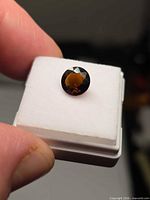 Round whiskey orange tourmaline on display pad, showing face-up brilliance