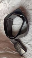 Full view of coiled black nylon belt showing buckle front and strap texture