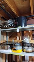 Shelved mix of stock pot, baking sheets, muffin tins, roasting pan, saucepans and casserole