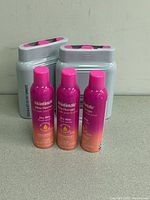 Front view of three Skintimate Dry Skin shave gel cans with packaging in background