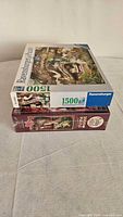 Stacked view of both puzzle boxes showing 1500-piece Ravensburger on top and 2000-piece sealed puzzle below