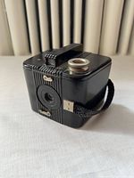Front three-quarter view showing lens, ribbed front, strap