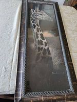 Full view of framed giraffe print within distressed wood frame