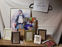 Overall lot showing two framed artworks and seven assorted empty frames on table
