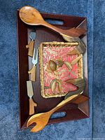 Lot overview showing tray, salad servers, cheese knives, woven basket and carved figures