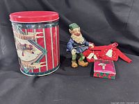 Group shot showing elf figurine, holiday tin, sweater ornaments and boxed brooch