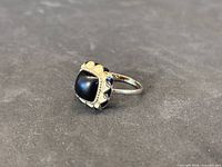 Perspective view showing front and design of gold ring with black cabochon stone