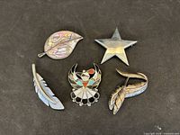 Group shot of all five sterling brooches on black background