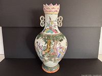 Front view showing figural panel, handles, lotus rim, reticulated base