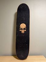 Top view of skateboard showing grip tape and skull graphic