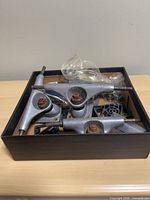 Box containing four silver Gullwing trucks, riser pads and hardware