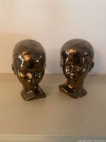 Front view of both ceramic mannequin head sculptures