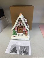 Front view of resin gingerbread house, box and instruction sheet visible