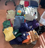 Pile of assorted shirts, polos and sweaters spread on floor