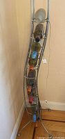 Full view of curved silver chrome wine rack in corner, bottles shown for scale