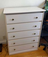 Front view of white 5-drawer dresser showing brass-tone knobs and overall condition